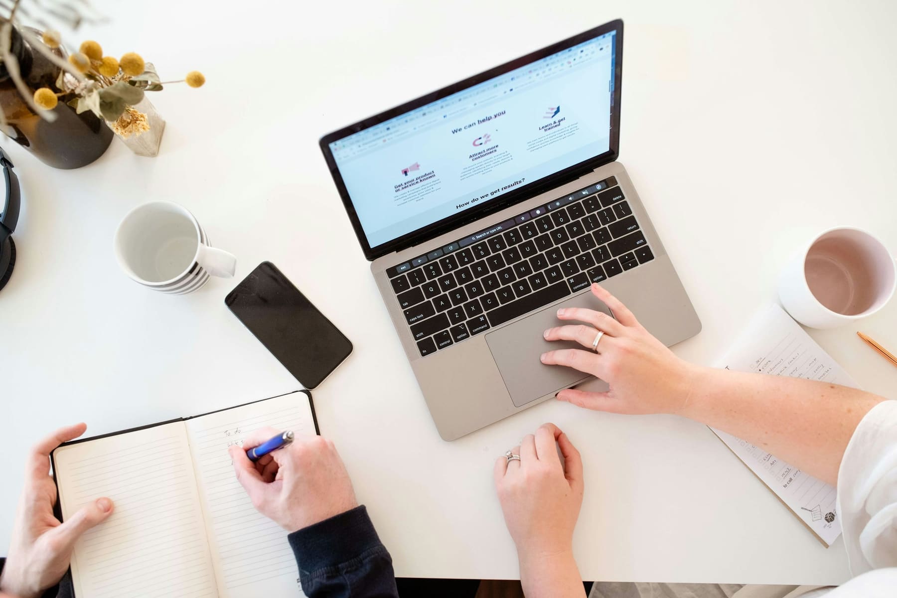 Two accountants collaborating over a laptop and notebook