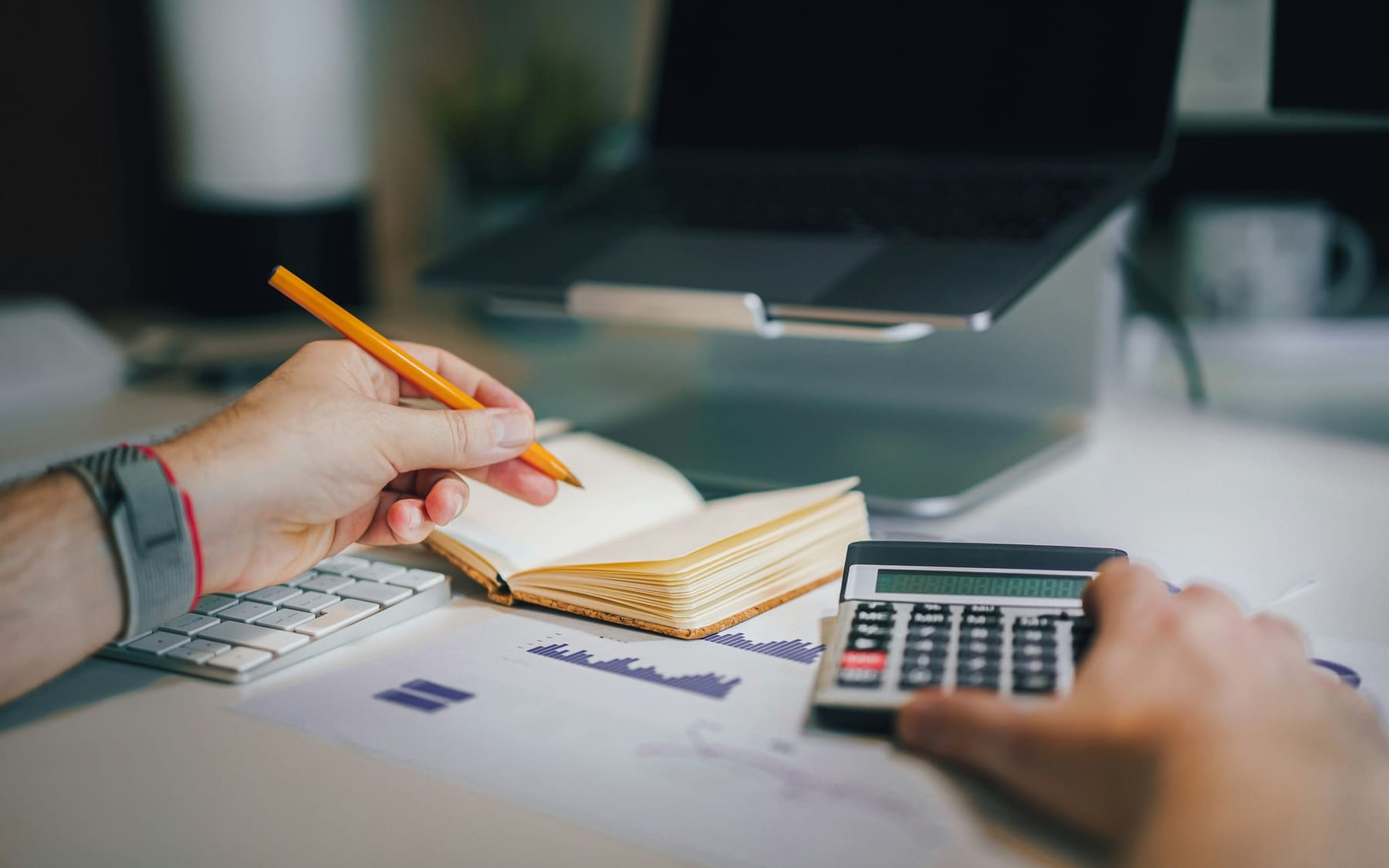 Bookkeeper checking figures with a calculator and financial reports