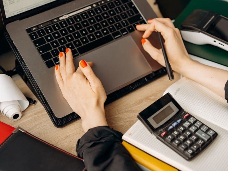 Bookkeeper working through figures on a laptop and calculator
