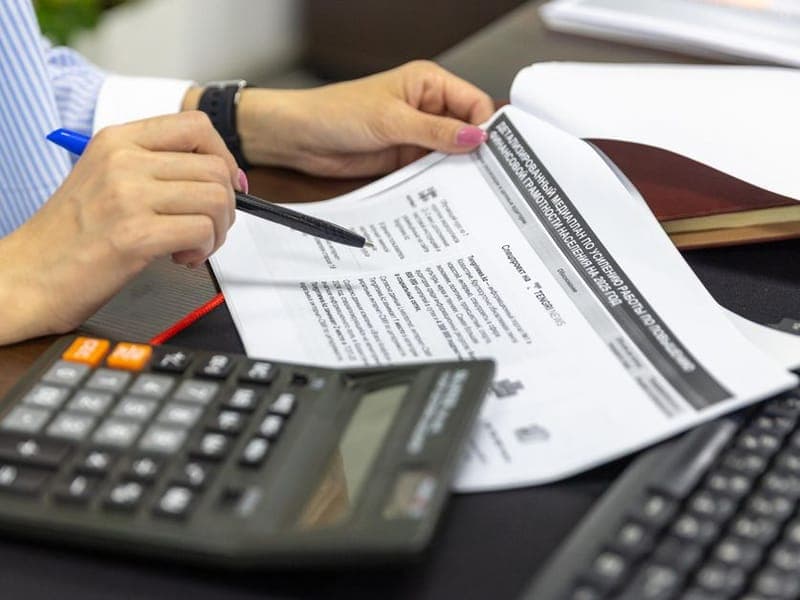 Close-up of a bookkeeper reviewing financial paperwork with a calculator