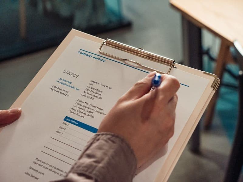 Hand signing an invoice on a clipboard