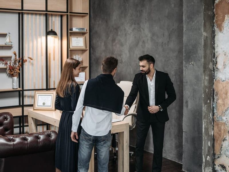 An advisor shaking hands with a client in an office